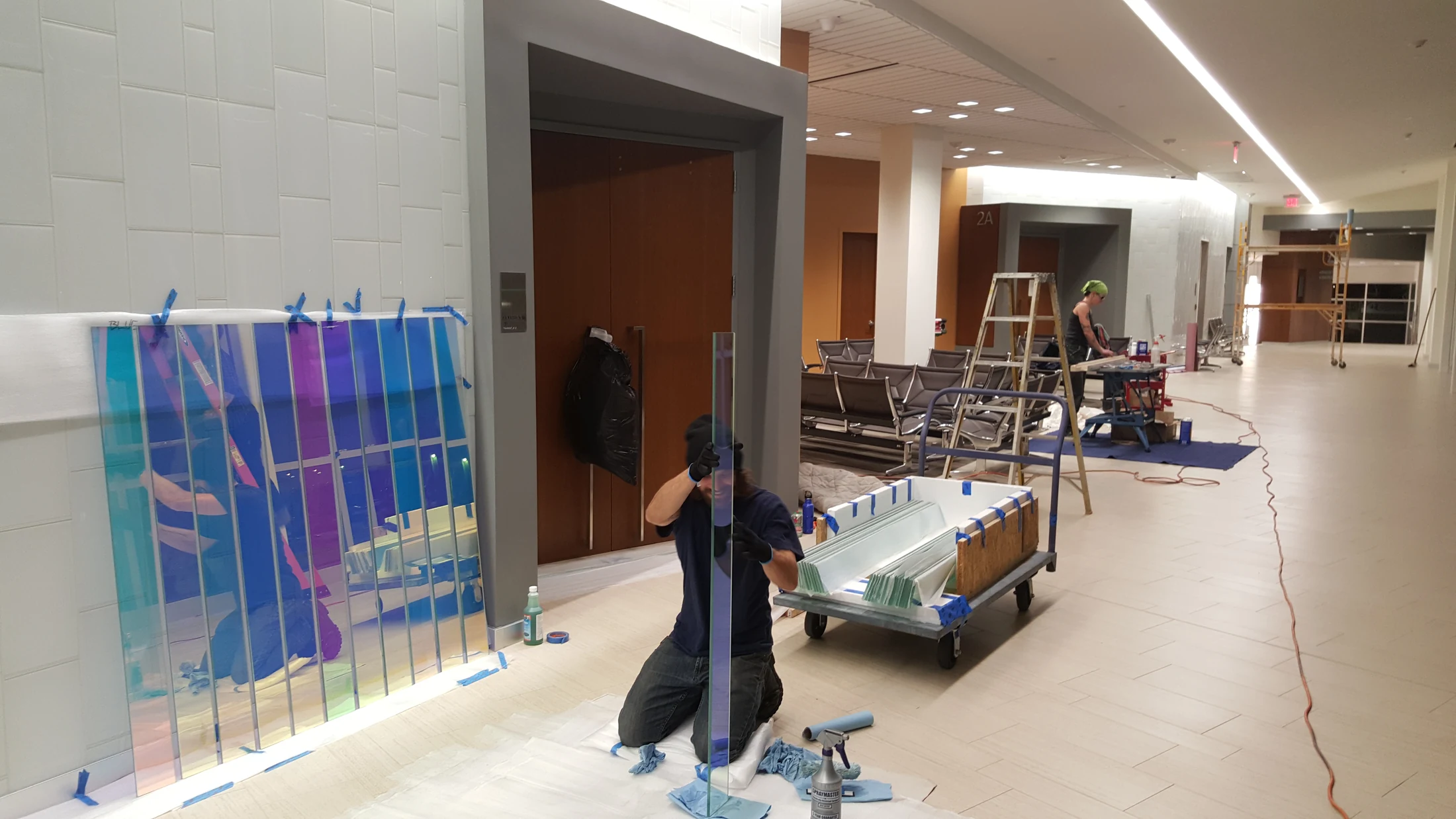 Crew installing long dichroic glass elements inside the courthouse