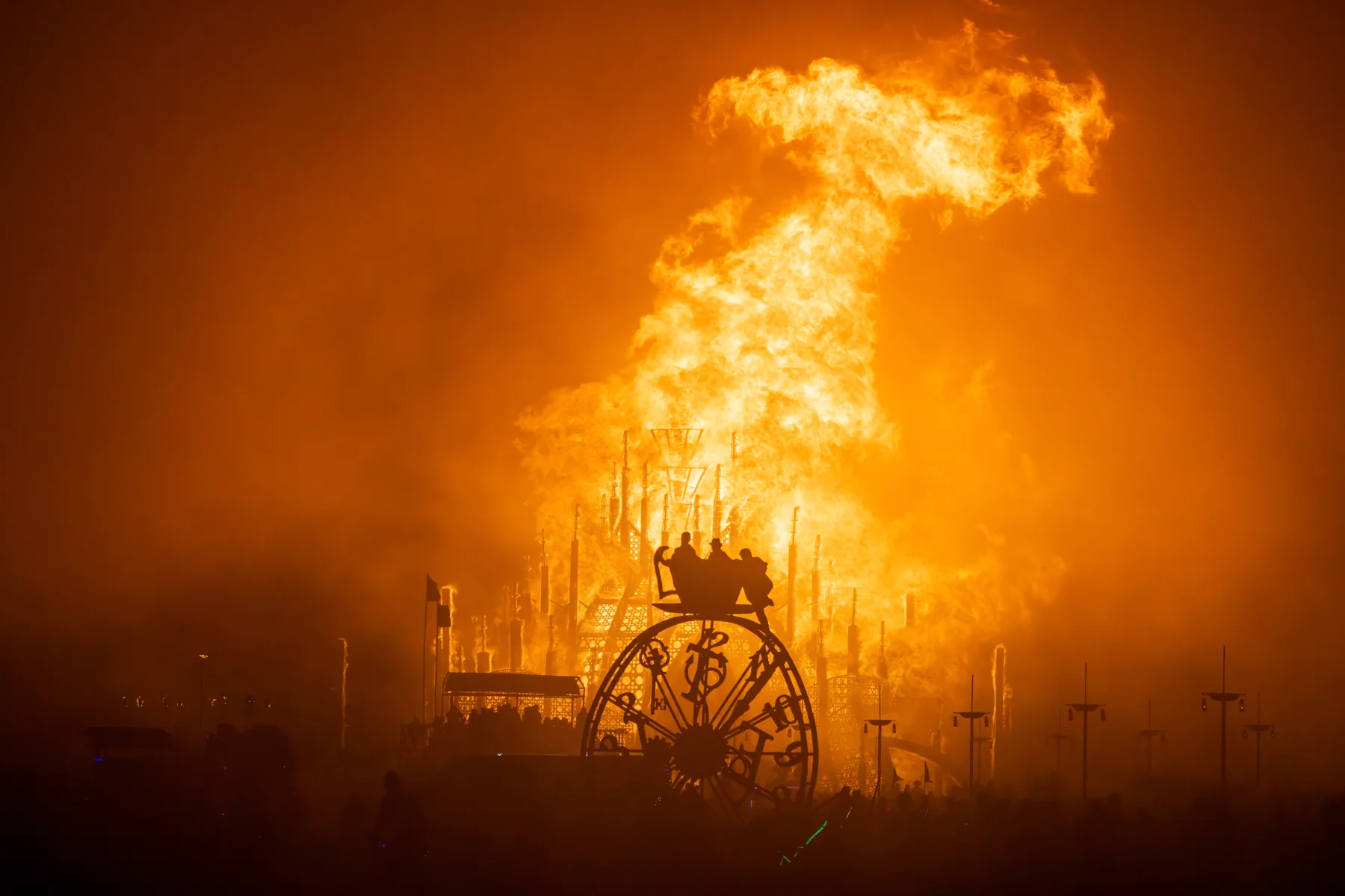 The End of Time at night with another Burning Man artwork burning in the background, photographed by Duncan Rawlinson